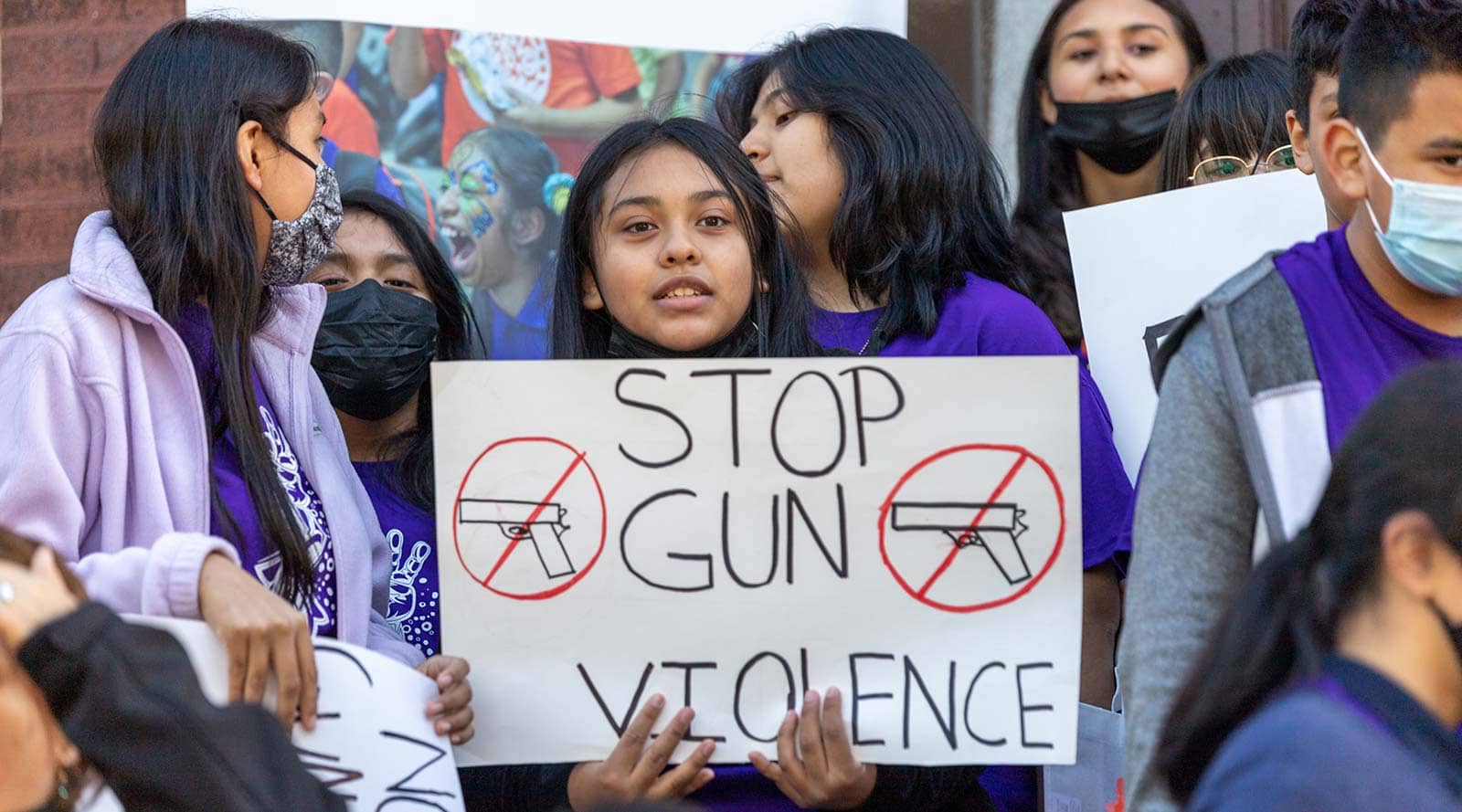 A girl holding a homemade sign reading 'Stop gun violence' at a peace march
