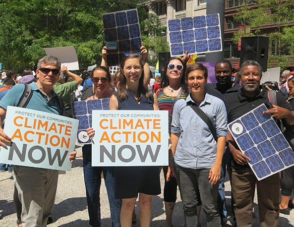 Elevate Energy staff members standing outside for an activist gathering with signs that read "Climate Action Now"