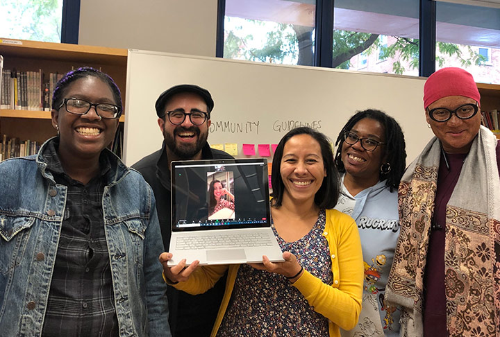 Group photo of five people from the Jews of Color Initiative holding up a laptop with a sixth person attending the meeting digitally onscreen